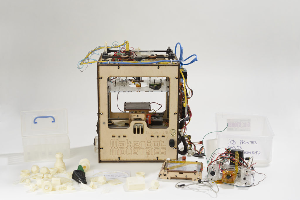 3D printer constructed out of plywood, surrounded by printed objects.